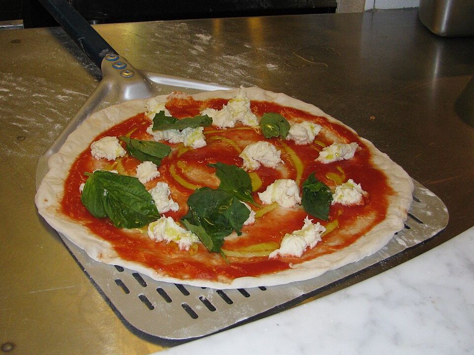 Pizza napolitana recién hecha sobre una pala perforada